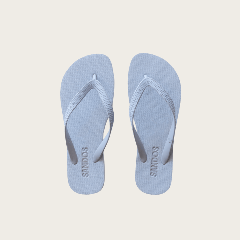 Pair of cornflower blue Sandos flip-flops on a beige background